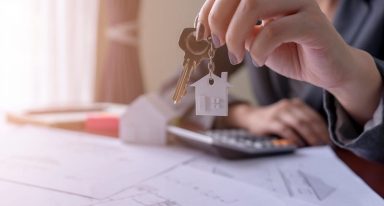 Mãos seguram chave sobre uma folha onde se encontra o desejo do projeto de um imóvel